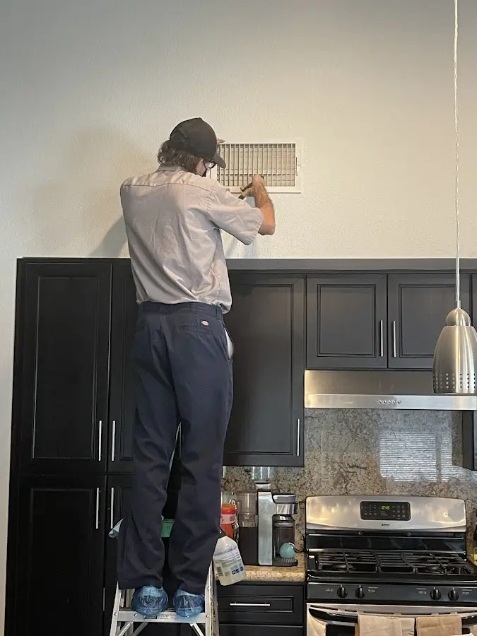 Technician inspecting an air vent during HVAC service in Brook Highland